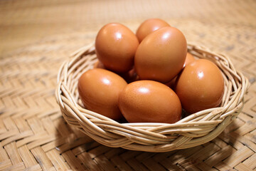Close-up view of raw chicken eggs in egg basket on brown wooden background