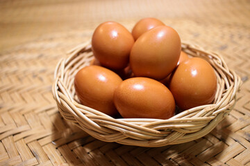 Close-up view of raw chicken eggs in egg basket on brown wooden background