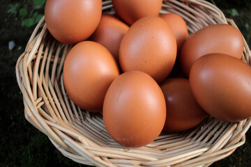 Close-up view of raw chicken eggs in egg basket on brown wooden background