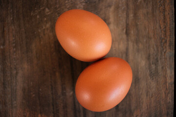 Close-up view of raw chicken eggs in egg basket on brown wooden background