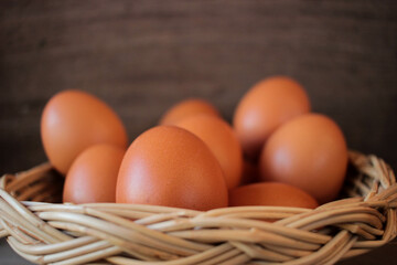 Close-up view of raw chicken eggs in egg basket on brown wooden background