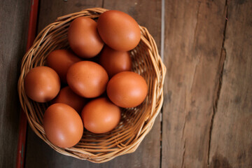 Close-up view of raw chicken eggs in egg basket on brown wooden background