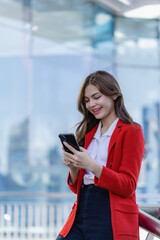 Fototapeta na wymiar Attractive woman happily standing and discussing work on the phone near her office building. Smiling woman holding smartphone talking to customer walking on outdoor street