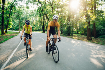 Couple riding bicycles outside of the city and wearing helmets and sunglasses