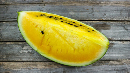 Yellow watermelon slices on wooden plate and isolated on gray board background. Healthy food, vegan. Antioxidant