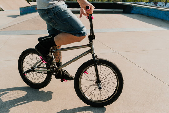 Cropped picture of a tattooed urban guy riding a bmx bike in a skate park.