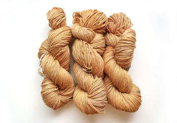 Beige twisted yarn hanks on a white background, hand dyed wool skeins flat lay top view