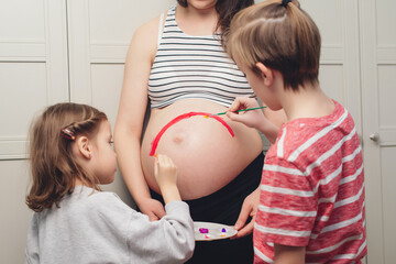 Happy kids painting pregnant belly their mother. Baby birth expecting time and belly painting.