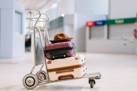 Trolley with suitcases and hat in airport terminal