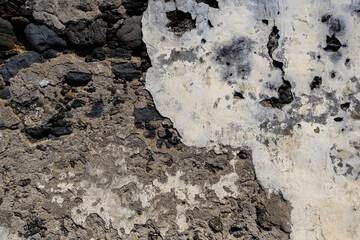 Detail of volcanic stone wall with worn out plaster coating