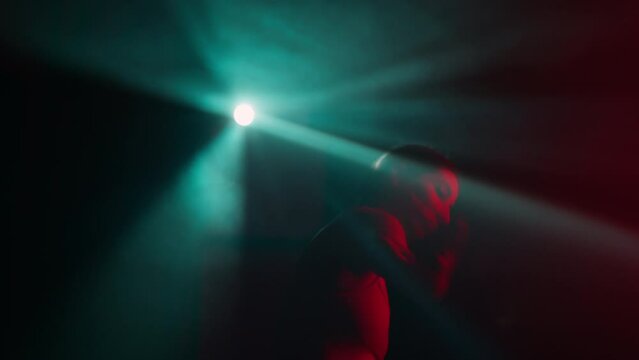 Woman dancer moves her body and hands sensually in blue and red light rays. Professional ballerina dances in dark atmosphere in spot of light at studio, contemporary art