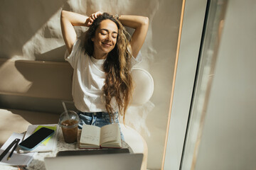 Young woman freelancer working in a coffeehouse, using her laptop and smartphone.