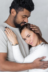 Multiethnic couple embracing at home.