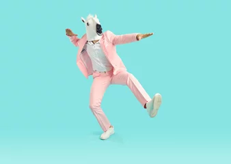 Keuken foto achterwand Carnaval Man in animal costume dancing and having fun. Funny guy with animal head dancing in studio. Full body length happy man in pink party suit and white horse mask dances isolated on bright blue background