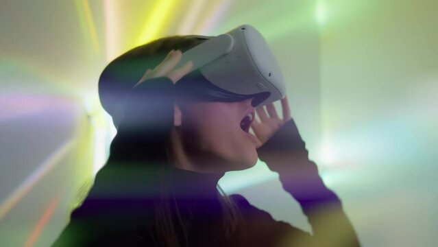 Attractive woman puts on virtual reality headset and dives in 3D world smiling. Female gamer emotionally exploring vr metaverse, looking around with excitement