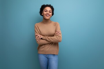 positive young bright latino woman with afro hair gathered in a ponytail against the background with copy space