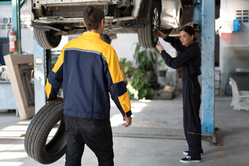 Caucasian man mechanic holding car tire with car lift background at car service	