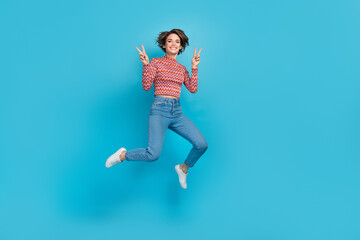 Fototapeta na wymiar Full length photo of friendly pretty lady wear pink shirt jumping high showing two v-signs empty space isolated blue color background