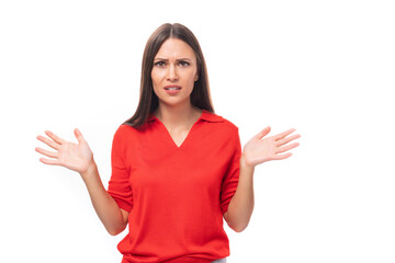 young caucasian female model with black straight hair dressed in a red t-shirt looks surprised on a white background with copy space