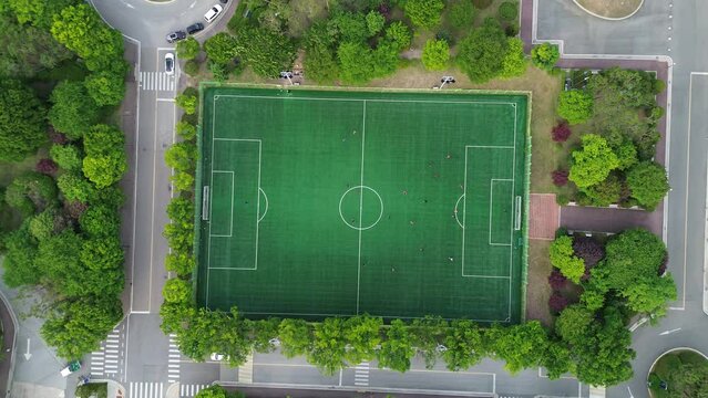 선수들이 분주히 공을 따라 뛰어다니는 대학교 축구경기장