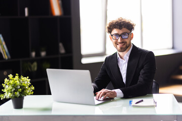 Businessman working in the office using touchpad while reading an e-mail on laptop and taking notes on the paper.