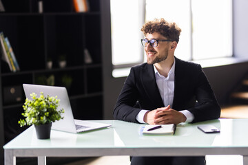 Creative business man working on a laptop in an open plan office.