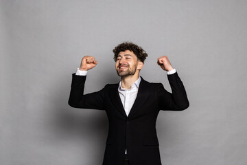 Young businessman celebrating his success isolated over gray background