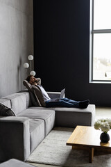 Time to relax. Handsome young man holding hands behind head while sleeping on the couch