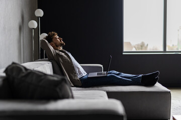 Time to relax. Handsome young man holding hands behind head while sleeping on the couch