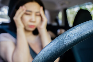 fatigued Asian woman suffering from headache migraine while driving feeling discomfort, stress, and exhaustion sitting in a car - obrazy, fototapety, plakaty