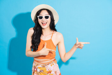 Portrait of a beautiful asian girl in a swimsuit smiling happily on a blue background