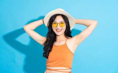 Portrait of a beautiful asian girl in a swimsuit smiling happily on a blue background