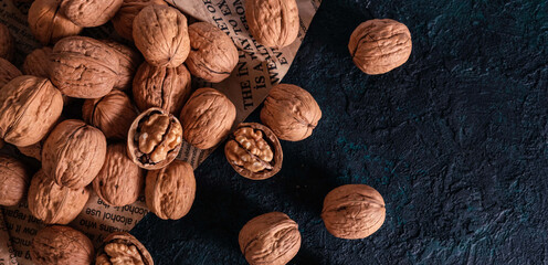 Shelled and unshelled walnuts on dark grunge background. Top view, flat lay with copy space.