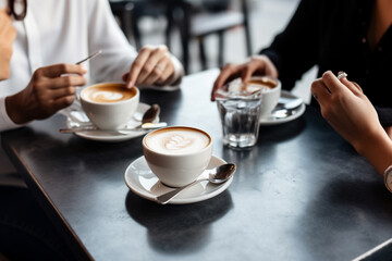 Friends talking at cafe table during coffee break, business meeting in coffee shop