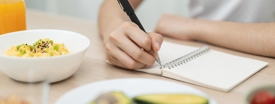 young female planning menu to eat ketogenic diet during weight loss program.