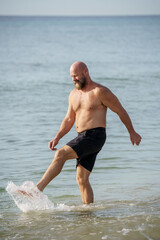 Florida man kicking up water on the beach sand