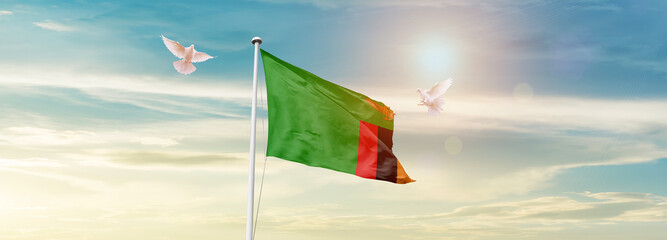 Waving Flag of Zambia in Blue Sky. The symbol of the state on wavy cotton fabric.