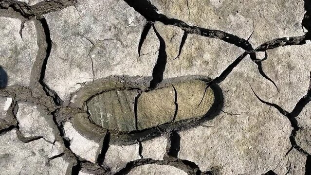 Footprint of boot or sneaker on dry cracked ground during great drought. Environmental catastrophe global warming