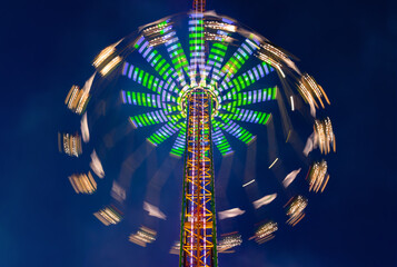 Merry-go-round or chairoplane with colorful led illumination at evening blue hour twilight. Magical circular light traces taken with long time exposure on a fun fair in Menden Sauerland Germany. 