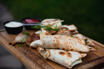 Chicken shawarma in pita bread with fresh vegetables, cream sauce and meat on a wooden background. Selective focus