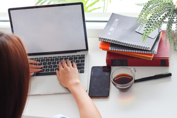 Fototapeta premium Young Asian businesswoman using laptop and notebook computers to work through internet to collect and organize investment documents. young businesswoman concept using technology to help investment