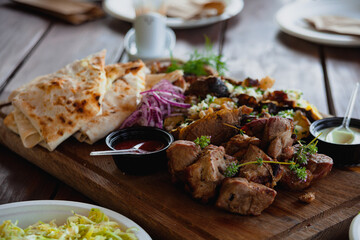 Close-up of meat slices with vegetables on a wooden board.