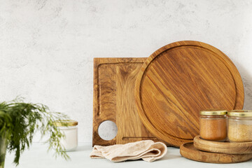Different kinds of chopping boards, wooden plates, spices, napkin on the kitchen table against wall
