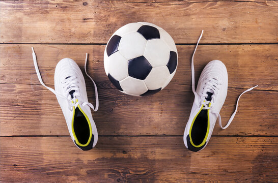 Football Boots And Ball Laid On A Wooden Floor Background