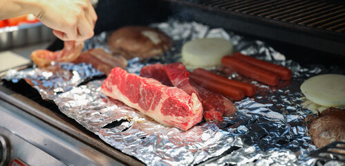 Barbecue grill with meat, shrimp, chicken, vegetables, and hand grilling food symbolizes festive outdoor cooking and celebration during a national holiday