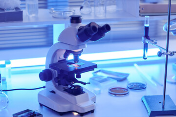 Close up of futuristic electronic microscope on laboratory workstation in neon light, copy space