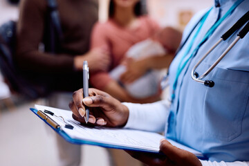 Close up of pediatric nurse writing data into medical record.