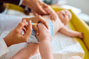 Close up of doctor giving vaccine to baby at pediatrician's office.