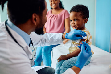 Smiling black boy receiving vaccine at pediatrician's office.