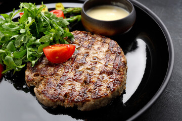 mouthwatering grilled pork steak topped with savory sauce, peppery arugula and ripe tomatoes